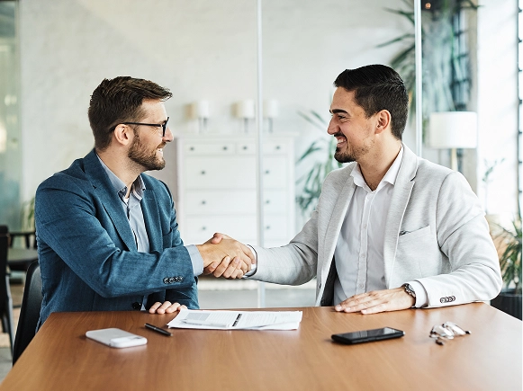 White label Beaver Builder trusted and proven — two professionals shaking hands during a meeting with documents on table, representing reliability and strong WordPress community support