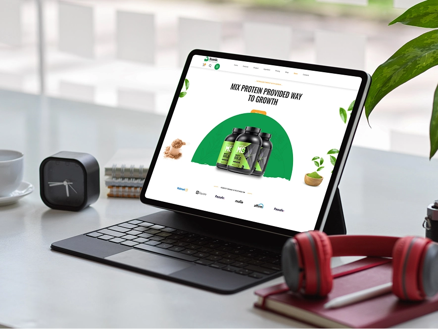 White label BigCommerce custom functionality and integrations — laptop displaying ecommerce product website with workspace items like headphones, notebook, and clock representing advanced development and integrations