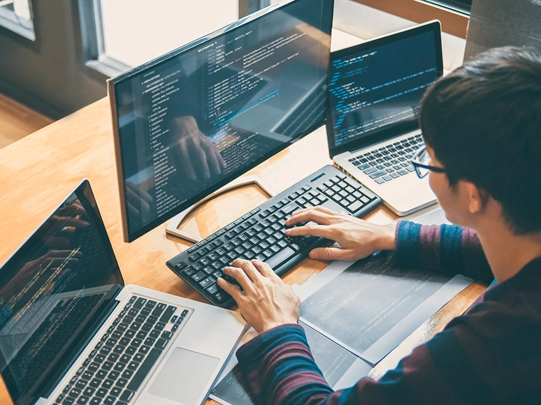 White label Elementor development workflow — developer coding custom website solutions with multiple laptops and advanced Elementor features