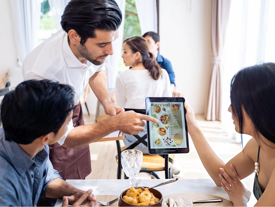 White label local SEO for restaurants — team reviewing menu and business strategy on tablet at dining table for improving local search presence