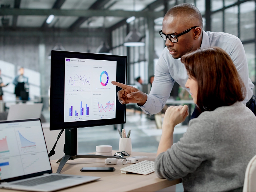 White label reporting and insights — two professionals analyzing desktop graphs with one explaining performance using hand gestures